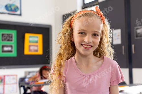 Preview: In school, young Caucasian girl with curly blonde hair is smiling in a classroom