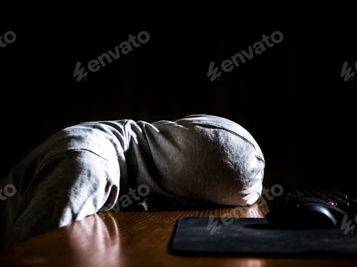 Preview: abstract anonymous person in the hood sleeping lying on the table in front of computer in the night