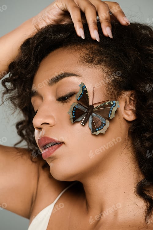 Preview: pretty african american woman with butterfly on cheek isolated on grey
