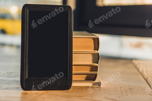 Preview: e-book with blank screen near paper books on table