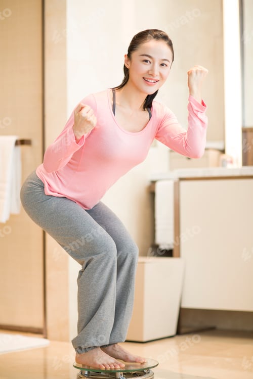 Preview: Young woman weighing herself on a scale