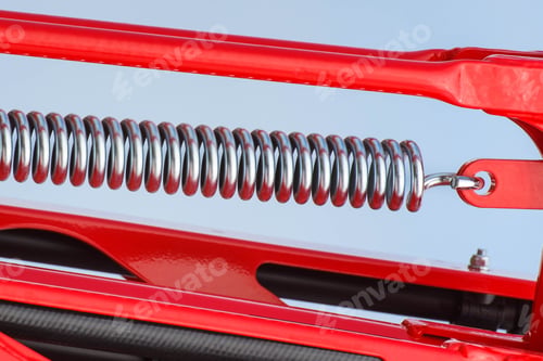 Preview: Hard spring made of steel. Part of big industrial or agricultural machine. Blue sky background