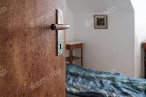 Preview: Open wooden door, against of a bed and room with white walls, with natural light from window