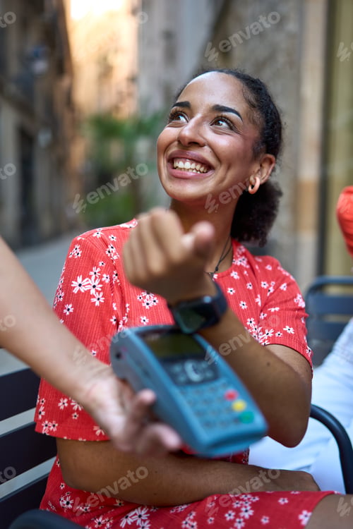 Preview: Woman using smart watch to pay in an outdoors cafeteria