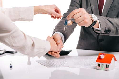 Preview: cropped view of mortgage broker shaking hands with woman and holding keys isolated on white,
