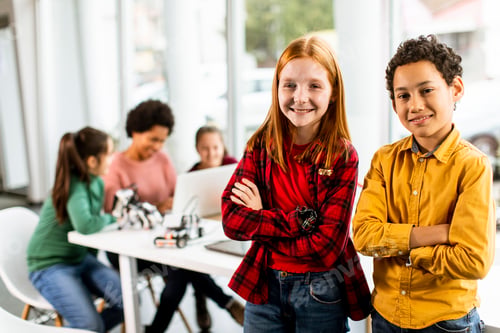 Preview: Best friends standing in front of kids programming electric toys and robots at robotics classroom