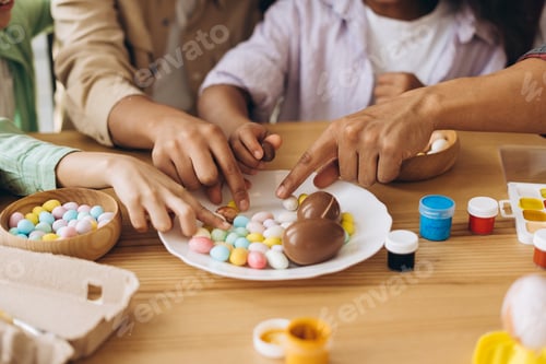Preview: Family painting easter eggs and enjoying chocolate treats during easter celebration
