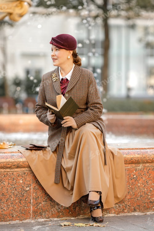 Preview: A brunette in vintage clothes and a hat with a book in her hands sits on a bench in an autumn park.