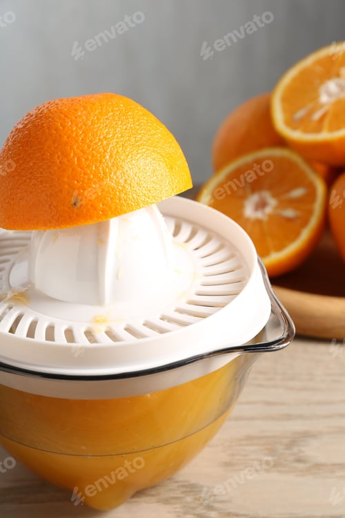 Preview: Making juice. Juicer and fresh oranges on wooden table, closeup