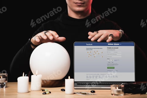 Preview: cropped view of esoteric near laptop with facebook website on screen isolated on black