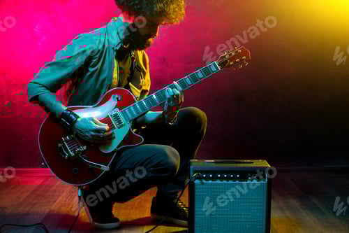 Preview: Man Playing Electric Guitar with Amplifier on Stage