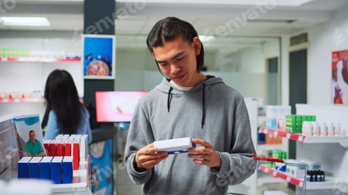 Preview: Young man checking boxes of supplements in drugstore