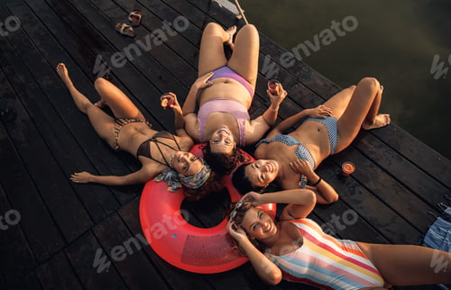 Preview: Group of female friends enjoying a summer day laying on the pier at the lake.