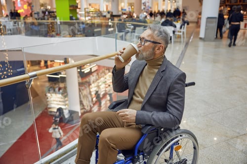 Preview: A stylish man enjoys his coffee while relaxing in a wheelchair at a modern mall setting
