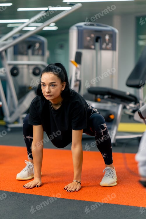Preview: a young girl in sportswear in the gym does stretching exercises before the start of training