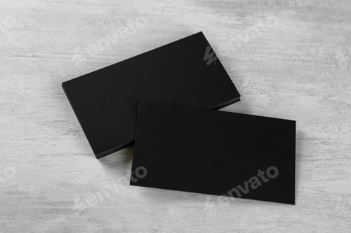 Preview: Blank black business cards on white table, above view. Mockup for design