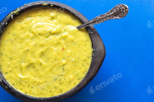 Preview: Top view of guacamole in a bowl with a spoon isolated on a blue background