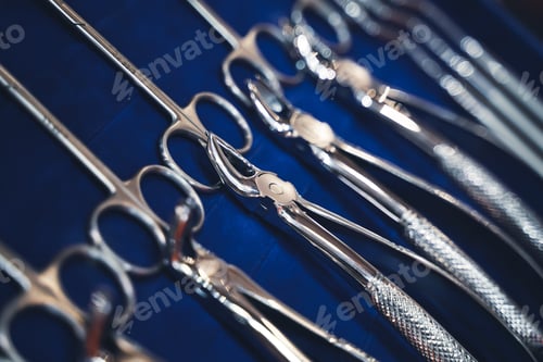 Preview: row of various dental tools on display on blue background with shallow depth of field