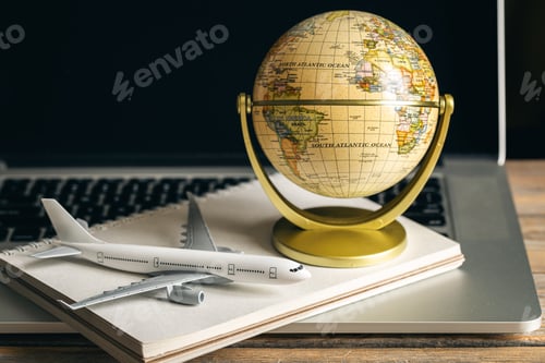 Preview: Travel composition with a model of an airplane and a globe on a wooden table.