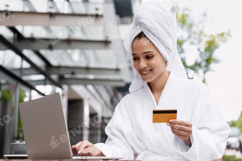 Preview: Relaxed woman shopping online with laptop and credit card on terrace