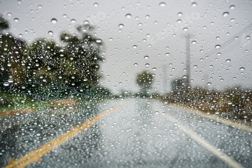 Preview: Raindrops on the windshield on a rainy day; empty street in the background; California