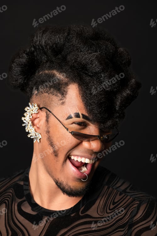 Preview: Young stylish man with extravagant hairstyle is laughing and wearing sunglasses and an earring