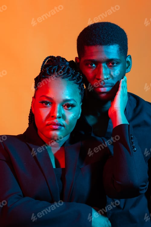 Preview: Portrait of young african american couple in love posing at studio dressed in classic clothes. Neon