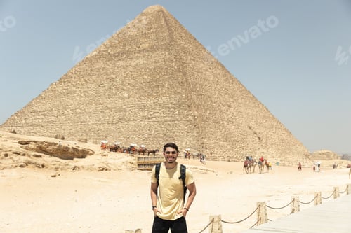 Preview: Young tourist male posing in front of the historic Pyramids in the Giza Plateau in Egypt