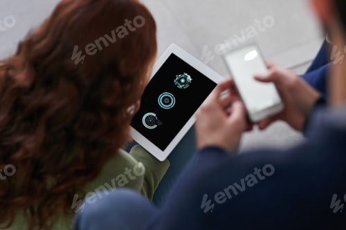 Preview: Shot of two business people using a cellphone and a tablet in an office