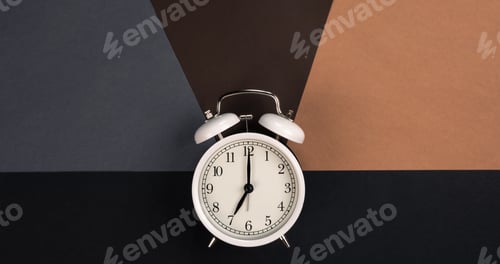 Preview: White alarm clock on a dark paper background, top view.