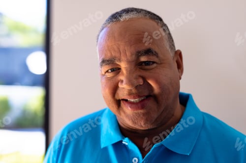 Preview: Close-up portrait of smiling biracial senior man against white wall in retirement home, copy space