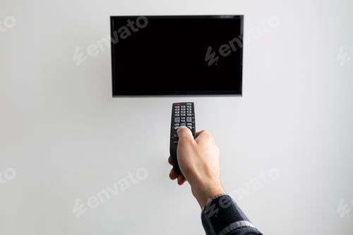 Preview: Hand Pointing Controller At Blank TV Screen On Wall Indoor