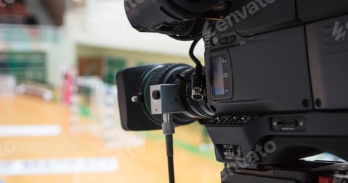 Preview: Camera ready to relay handball match. Blurred court background. Details of camera.