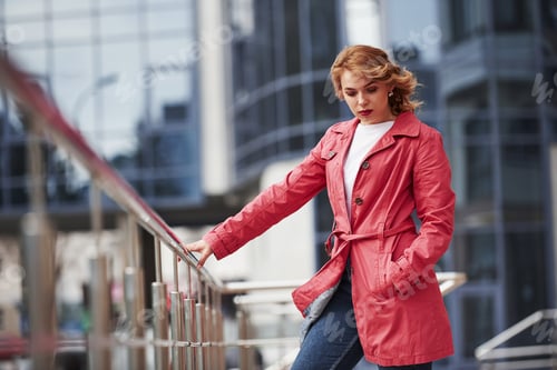 Preview: Holding by railings. Adult pretty woman in warm red coat have walk in the city at her weekends time