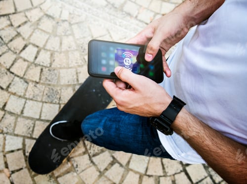 Preview: Young adult man using a smartphone music application outdoors