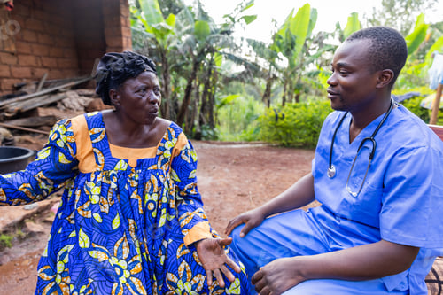 Preview: A doctor talks to his elderly patient during a home visit in an African village