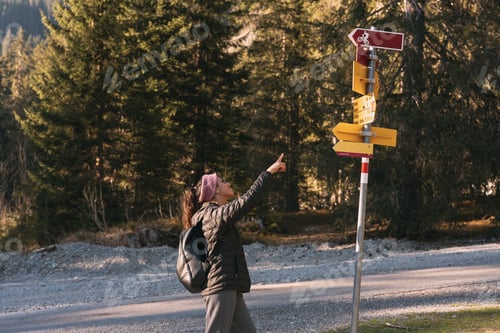 Preview: Hiker pointing at trail sign in mountain forest choosing path