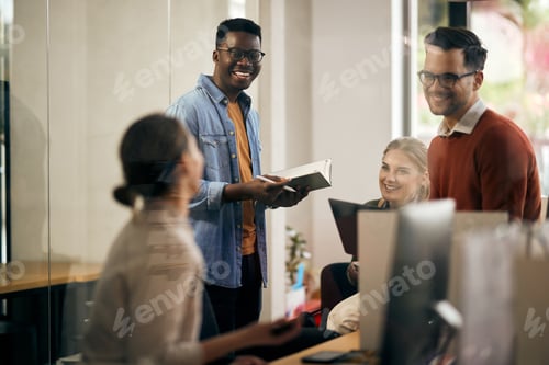 Preview: Happy black entrepreneur communicating with his colleagues during business meeting in the office.