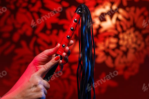 Preview: With tenderness a woman holds a leather whip adorned with a red handle