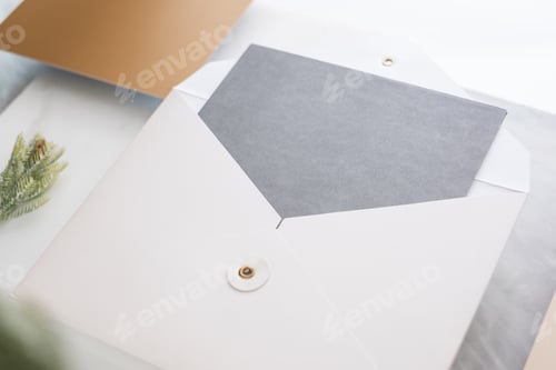 Preview: Top view of blank grey card in white envelop with pine leaf on two layer step of marble table