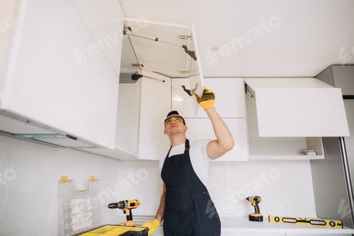 Preview: Maintenance man installing kitchen furniture