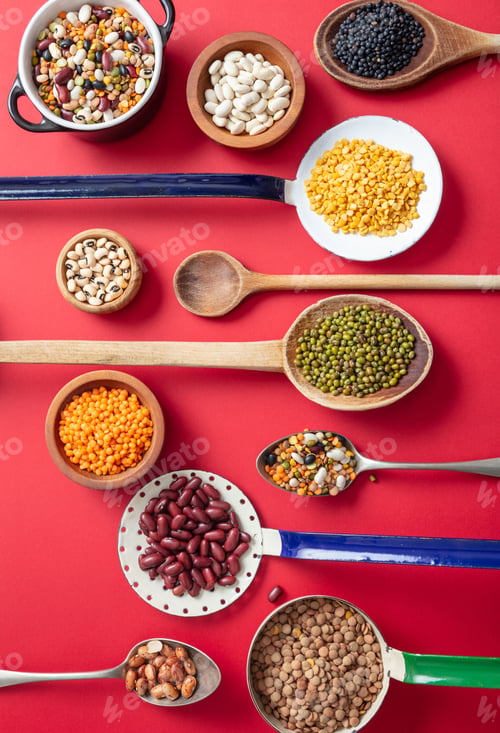 Preview: Top view flat lay of assortment of legumes on red tabletop