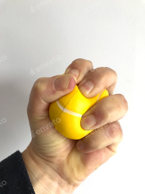 Preview: Yellow stress ball in a clenched fist against white background with copy space
