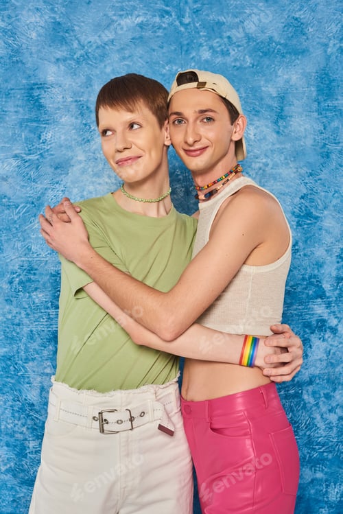 Preview: young lgbtq friends with colorful beads standing in casual clothes and hugging each other while