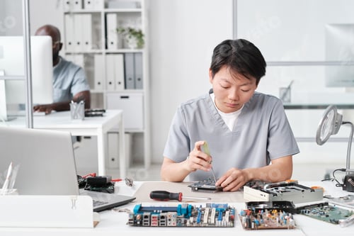 Preview: Young Chinese woman in uniform fixing tiny details of circuit board