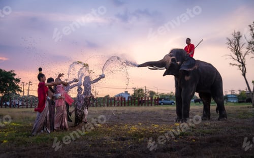 Preview: Asian people wearing Thai dress traditional pose happiness to playing splash water with Thai elephan