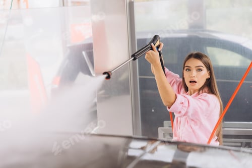 Preview: Young Woman Using High Pressure Washer At Car Wash