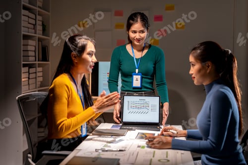 Preview: Three women are sitting at a table with a laptop in front of them