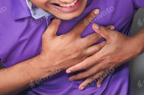 Preview: young man suffering pain in heart and holding chest with hand