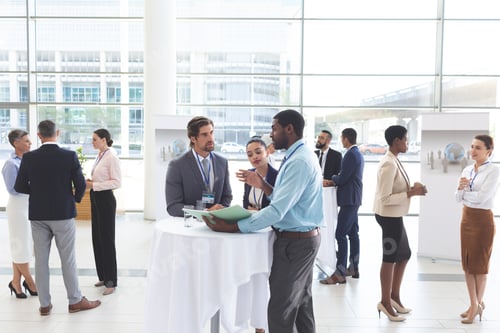 Preview: Business people discussing over documents at table after a conference in office lobby